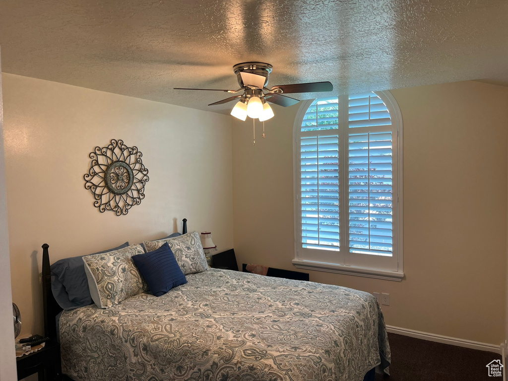 Bedroom with ceiling fan and a textured ceiling