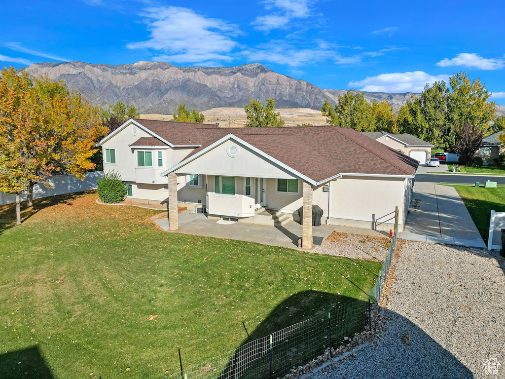 View of front of house with a patio, a mountain view, and a front yard