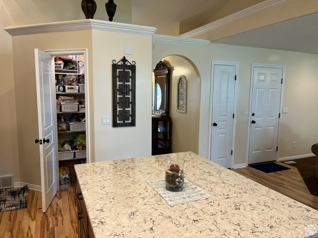 Kitchen featuring light stone counters, ornamental molding, and hardwood / wood-style flooring