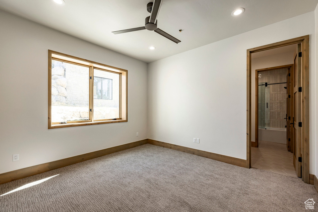 Unfurnished bedroom with ceiling fan, connected bathroom, and light carpet