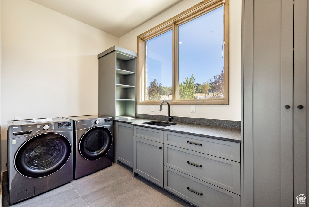 Washroom featuring washer and dryer, sink, light tile patterned floors, and cabinets