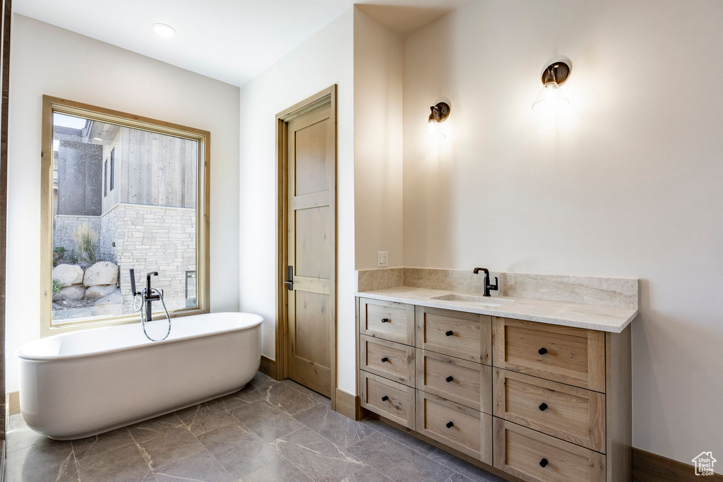 Bathroom featuring a bath, tile patterned flooring, and vanity