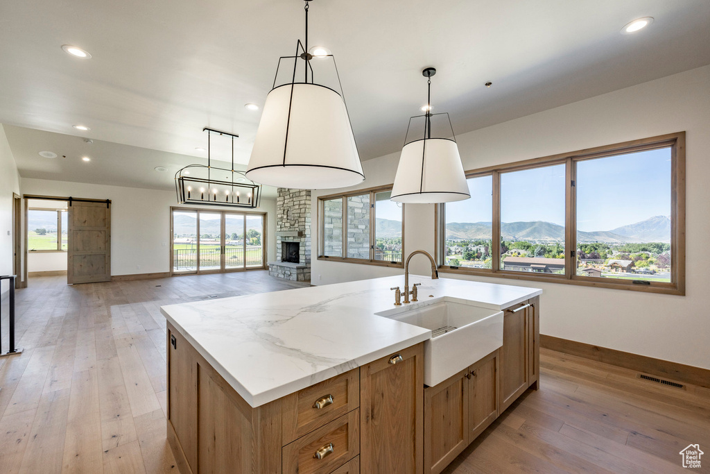 Kitchen featuring light hardwood / wood-style flooring, a mountain view, pendant lighting, a kitchen island with sink, and a fireplace