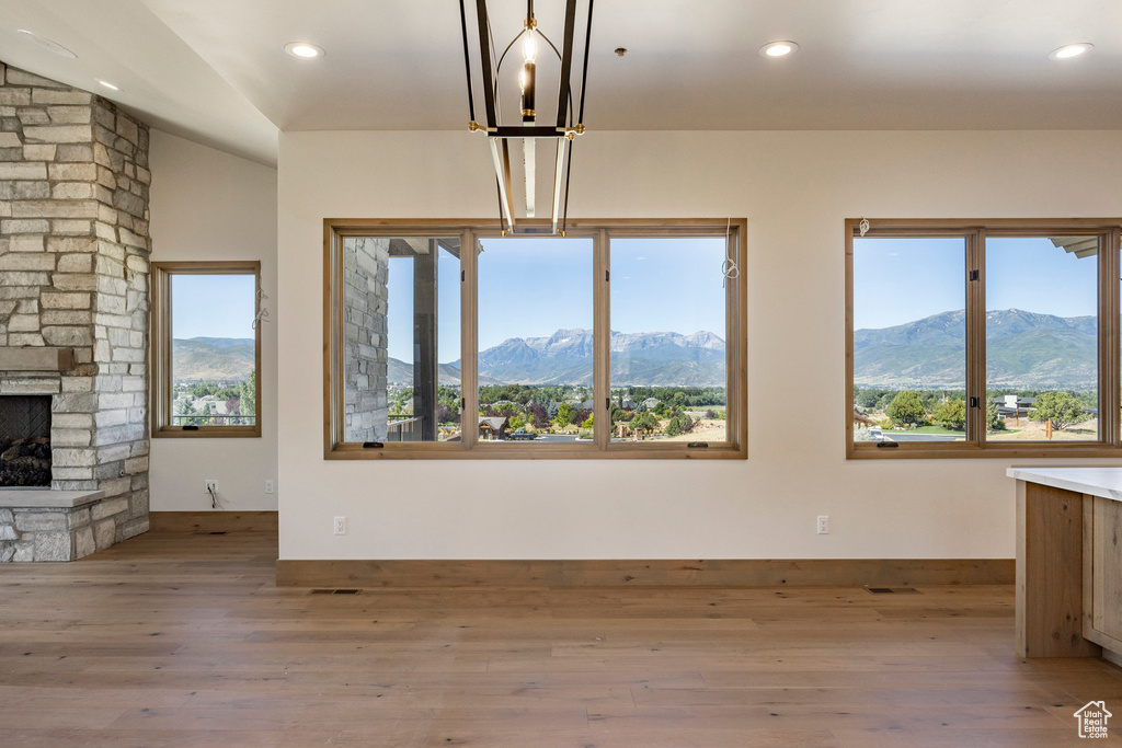 Unfurnished living room with plenty of natural light, a mountain view, a stone fireplace, and light hardwood / wood-style flooring