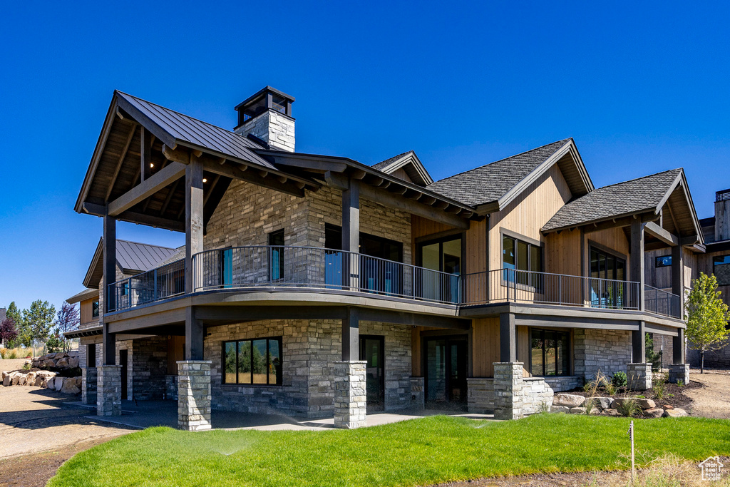 Rear view of property with a balcony and a lawn