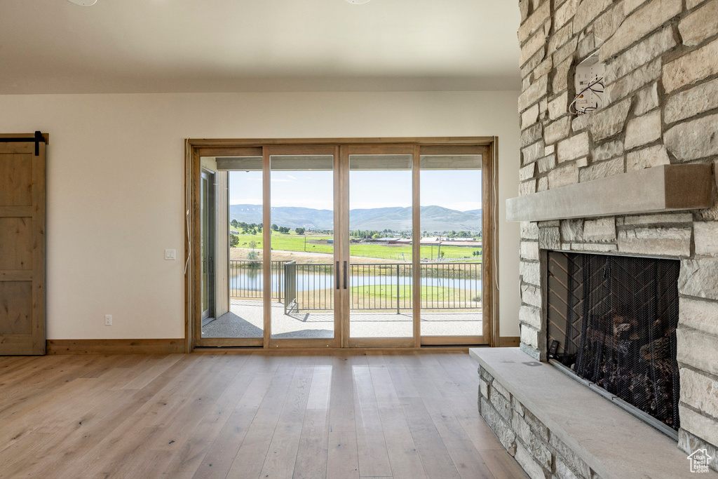 Unfurnished living room with a barn door, plenty of natural light, and light hardwood / wood-style flooring