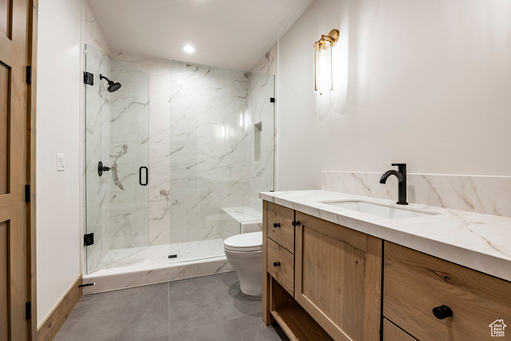 Bathroom featuring tile patterned floors, toilet, walk in shower, and vanity