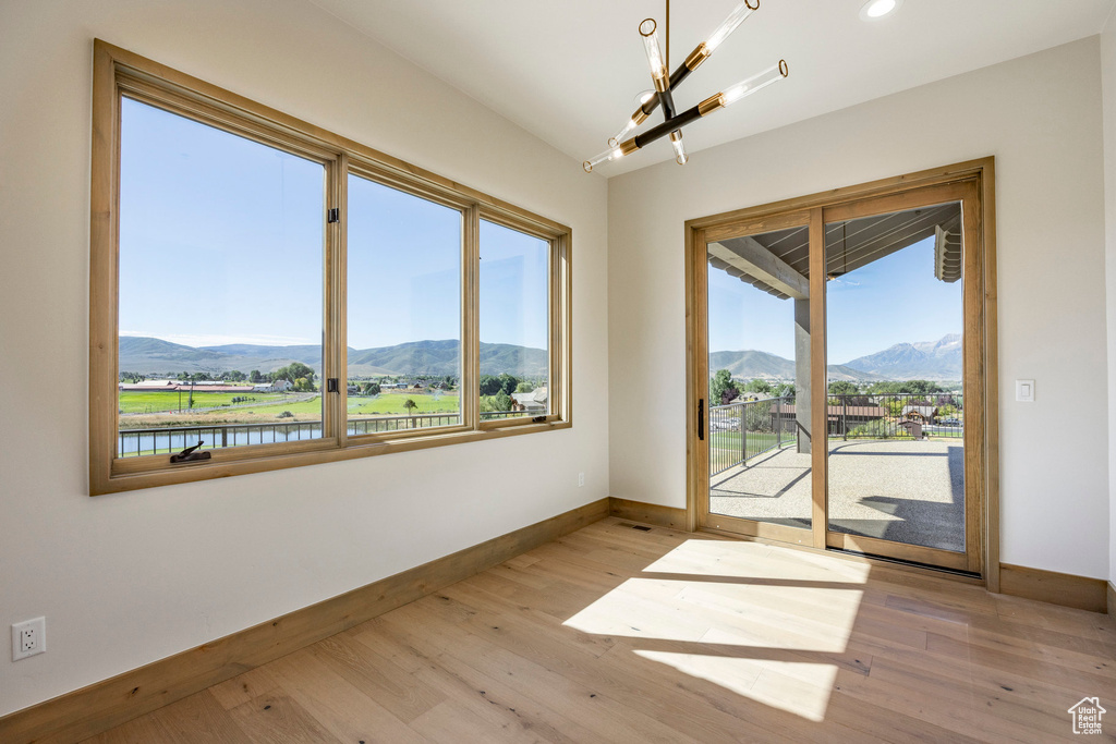 Spare room featuring a mountain view, a chandelier, and light wood-type flooring