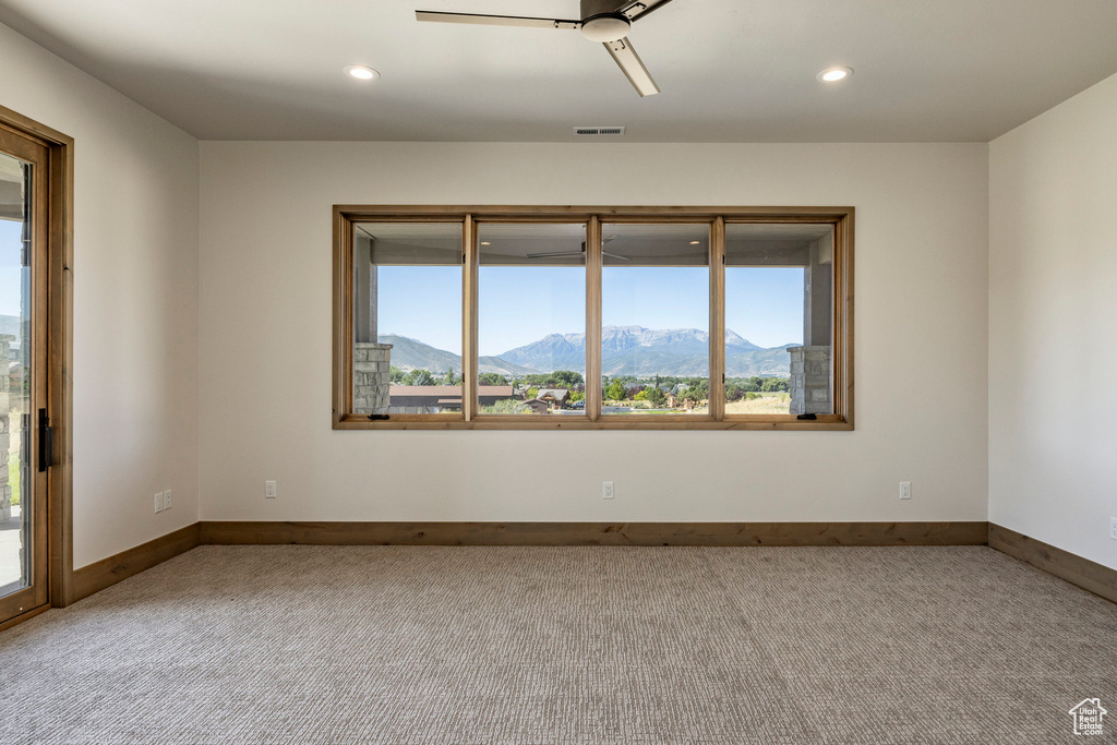 Carpeted spare room with a mountain view and ceiling fan