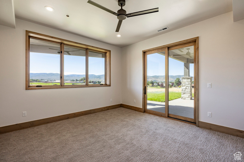 Carpeted empty room with ceiling fan and a mountain view