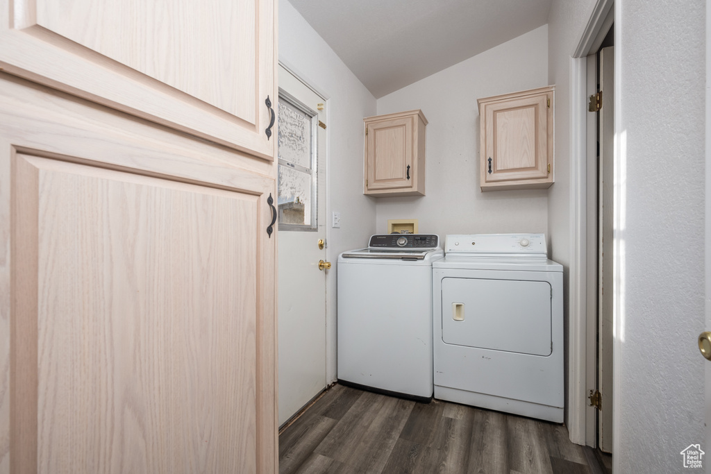 Washroom featuring washing machine and clothes dryer, dark hardwood / wood-style flooring, and cabinets