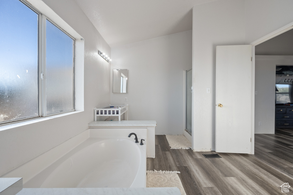 Bathroom with hardwood / wood-style flooring, shower with separate bathtub, lofted ceiling, and vanity