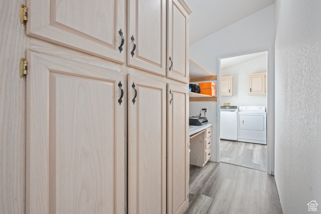 Laundry room with light wood-type flooring, cabinets, and washing machine and dryer