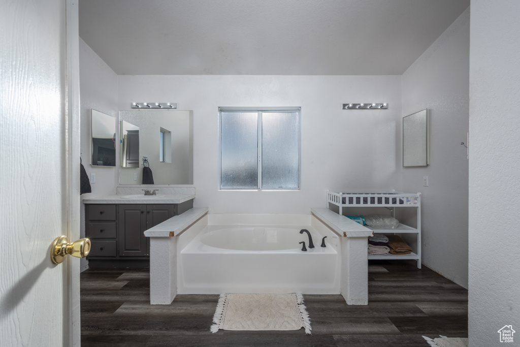 Bathroom with hardwood / wood-style flooring, a bath, and vanity