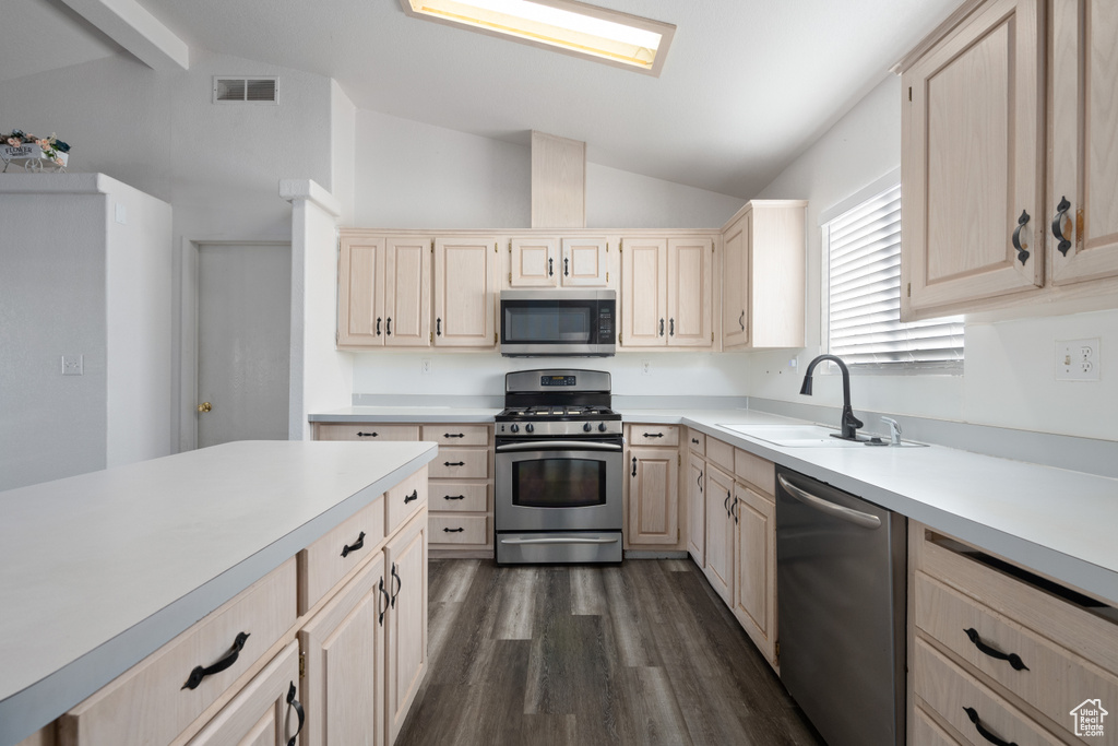 Kitchen featuring stainless steel appliances, lofted ceiling with beams, sink, light brown cabinets, and dark hardwood / wood-style flooring