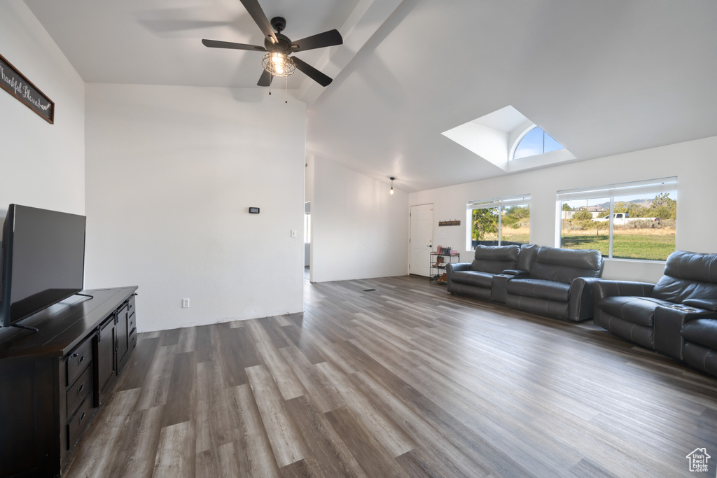 Living room with ceiling fan, wood-type flooring, and lofted ceiling with skylight