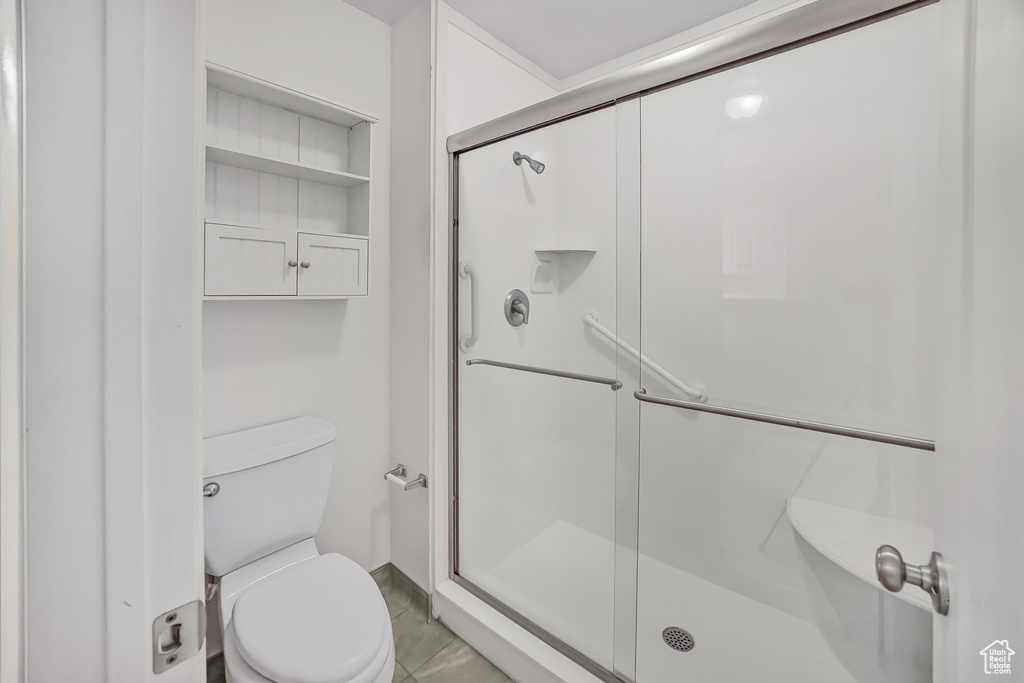 Bathroom featuring tile patterned flooring, toilet, and an enclosed shower