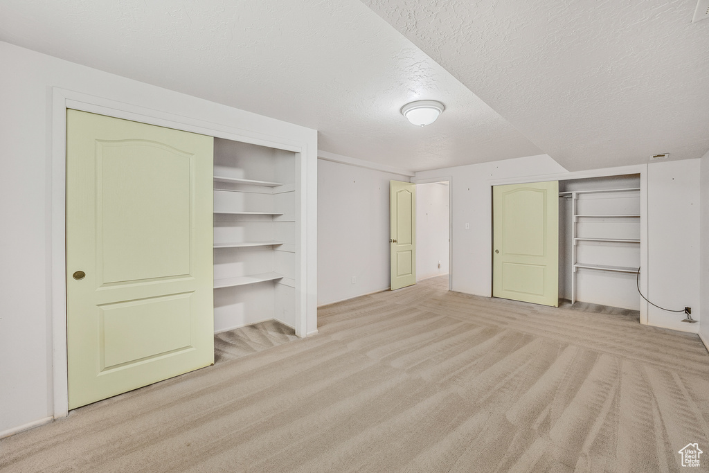 Basement featuring a textured ceiling and light carpet