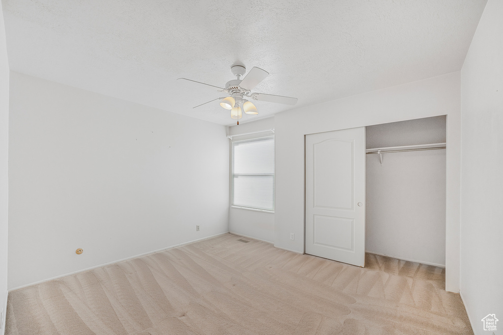 Unfurnished bedroom featuring a closet, ceiling fan, and light carpet