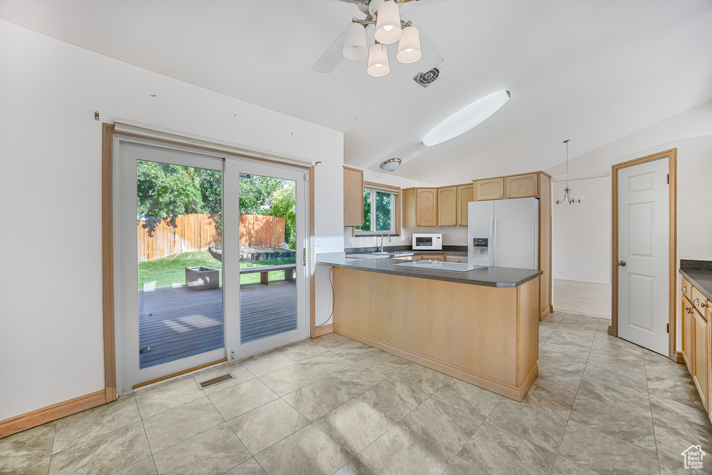 Kitchen with sink, light tile patterned floors, kitchen peninsula, white appliances, and vaulted ceiling