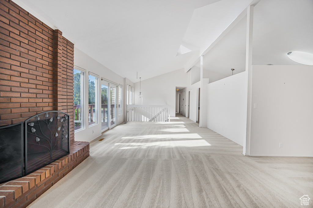 Carpeted living room featuring vaulted ceiling and a wood stove