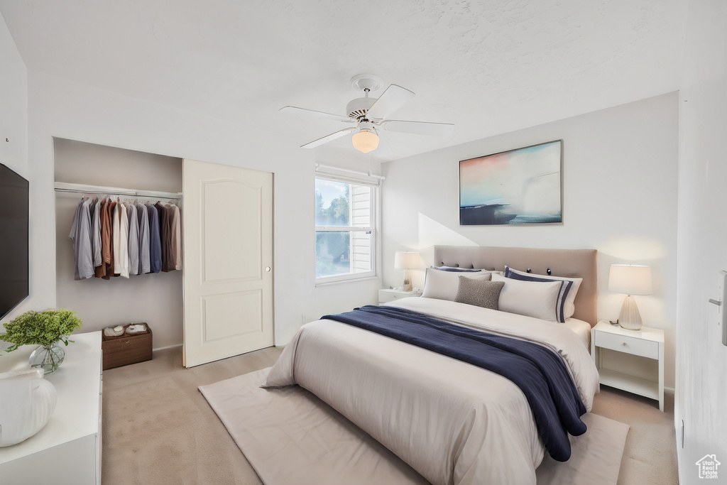 Carpeted bedroom with ceiling fan and a closet