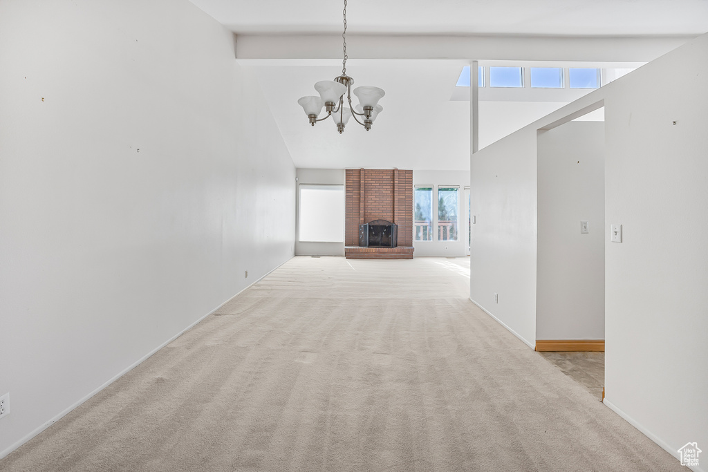 Unfurnished room featuring high vaulted ceiling, a healthy amount of sunlight, an inviting chandelier, and light colored carpet