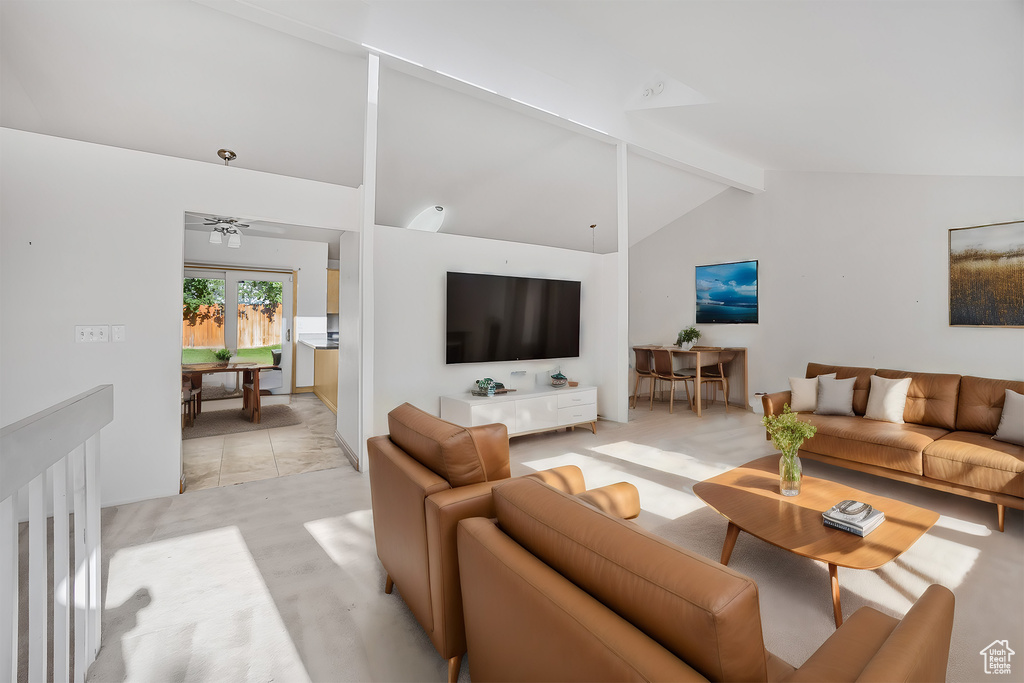 Living room featuring ceiling fan, light tile patterned floors, and vaulted ceiling with beams