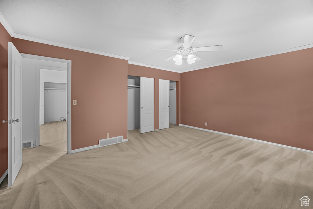 Unfurnished bedroom with ceiling fan, ornamental molding, and light carpet