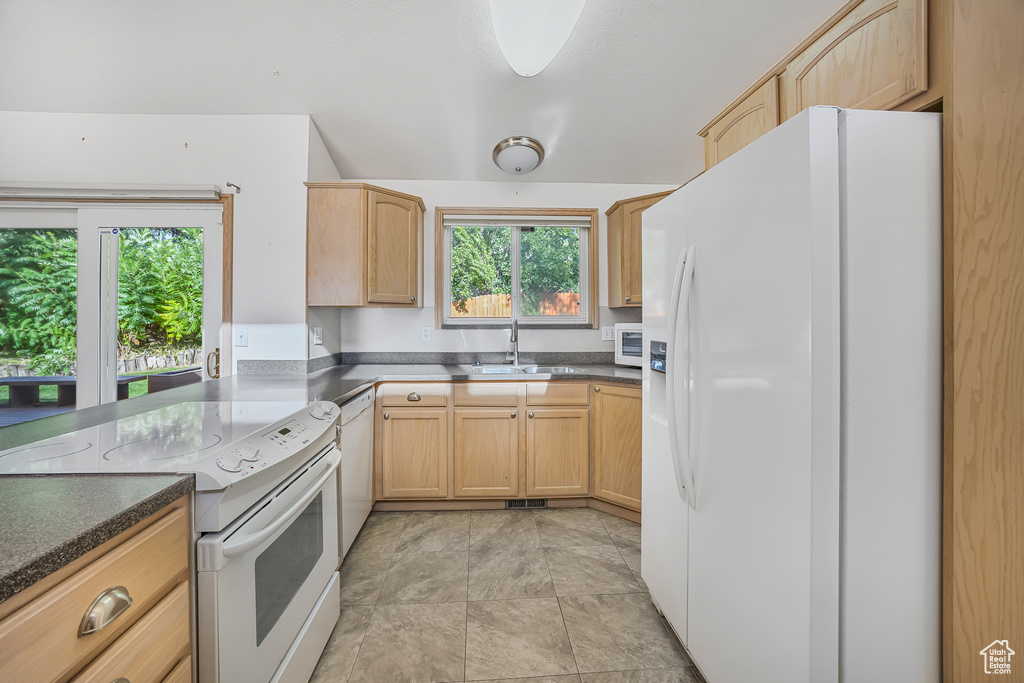 Kitchen with sink, white appliances, light brown cabinetry, and light tile patterned floors