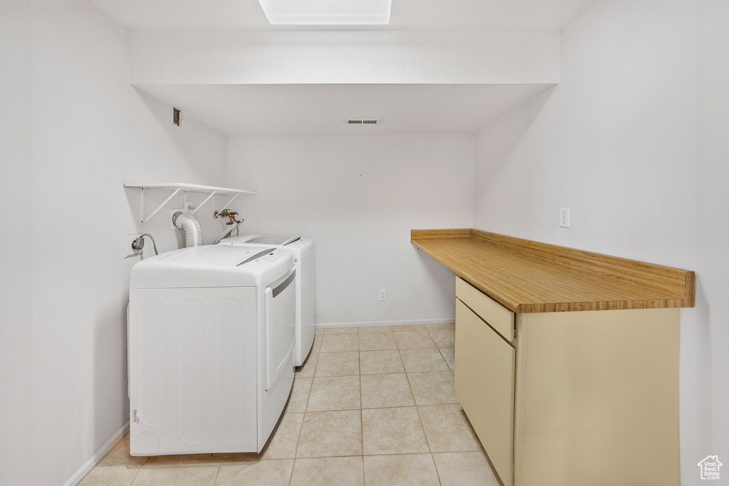 Clothes washing area with independent washer and dryer and light tile patterned flooring