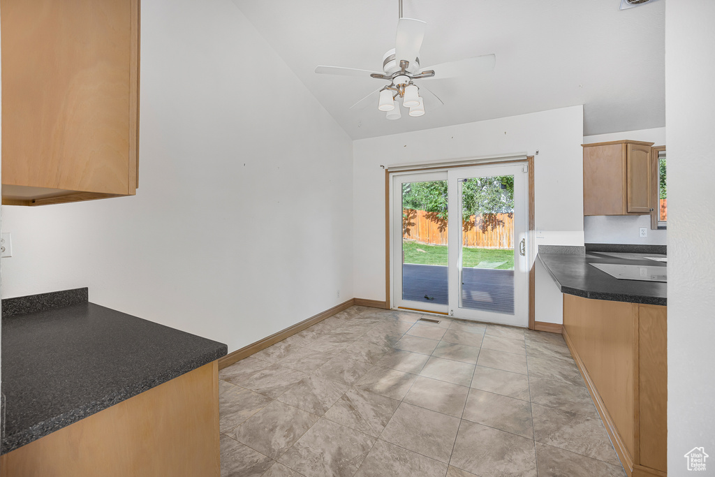 Interior space featuring ceiling fan, light tile patterned floors, and lofted ceiling