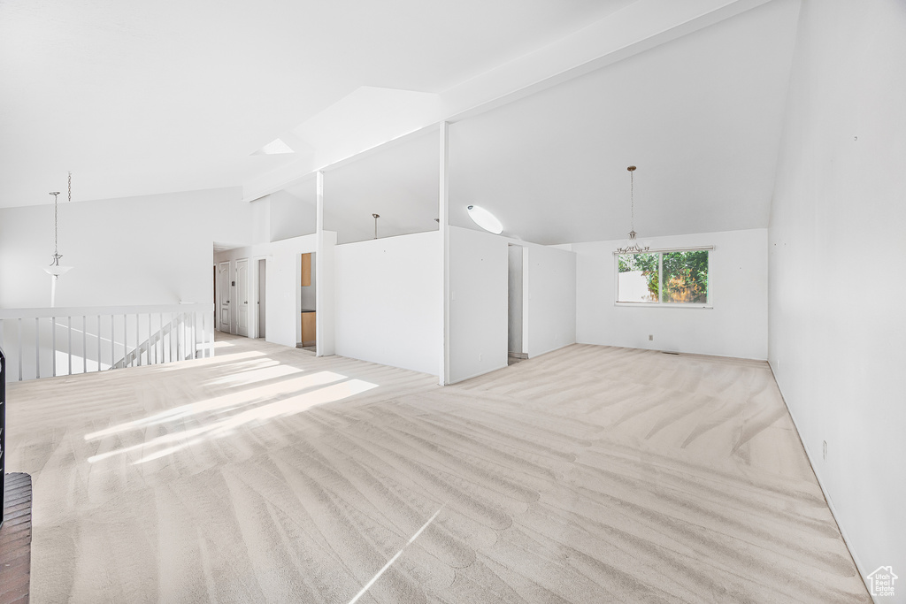 Carpeted spare room with high vaulted ceiling, beamed ceiling, and a notable chandelier