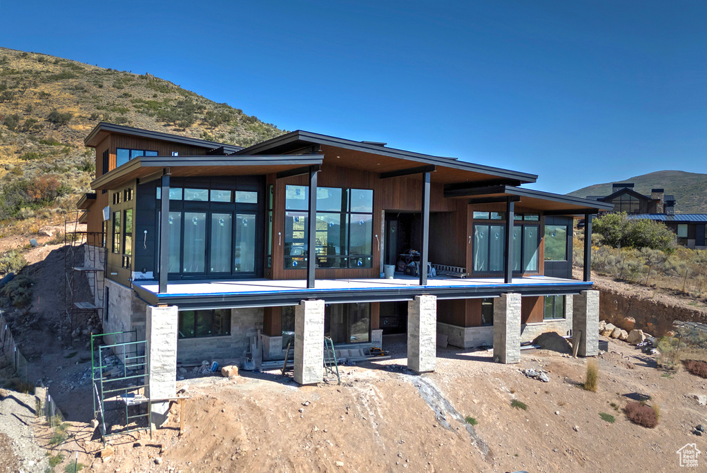 Rear view of house with a sunroom, a mountain view, and a patio area