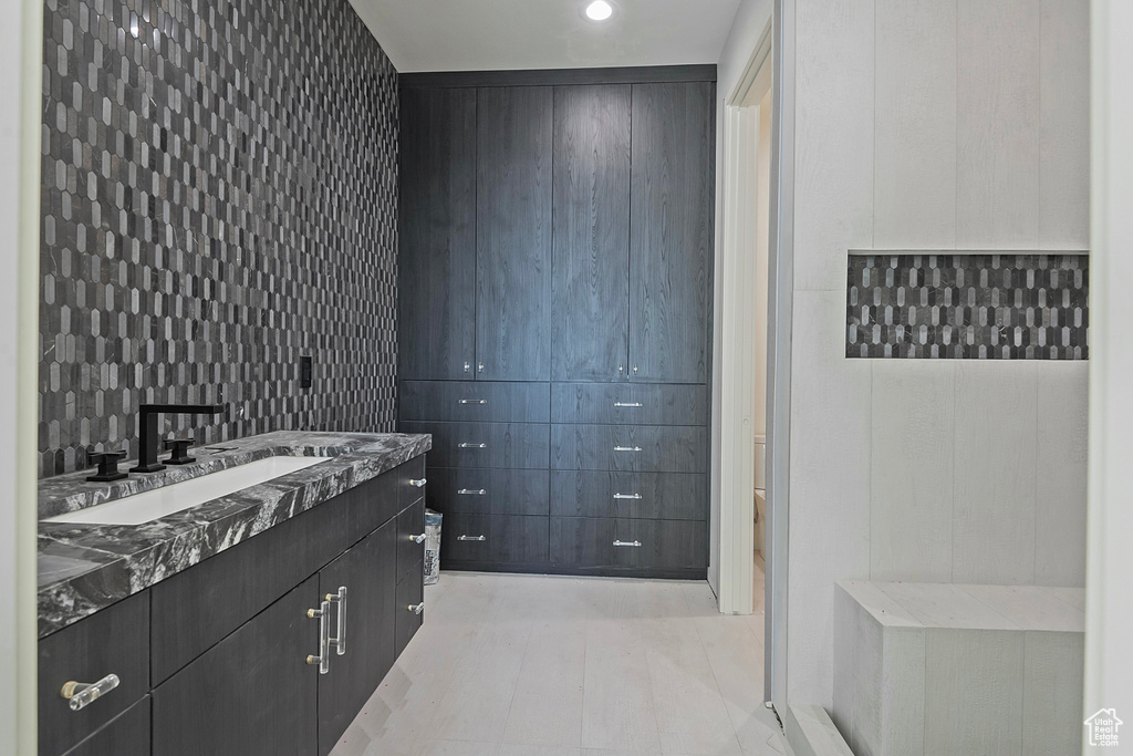 Bathroom featuring tile walls, vanity, and toilet