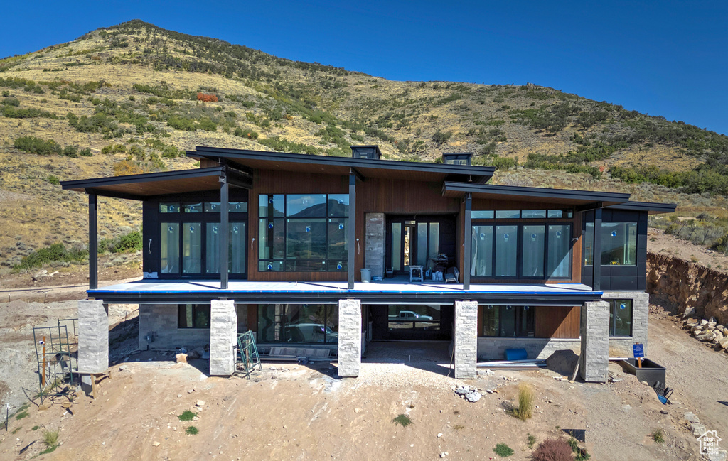 Rear view of house featuring a sunroom, a patio, and a mountain view