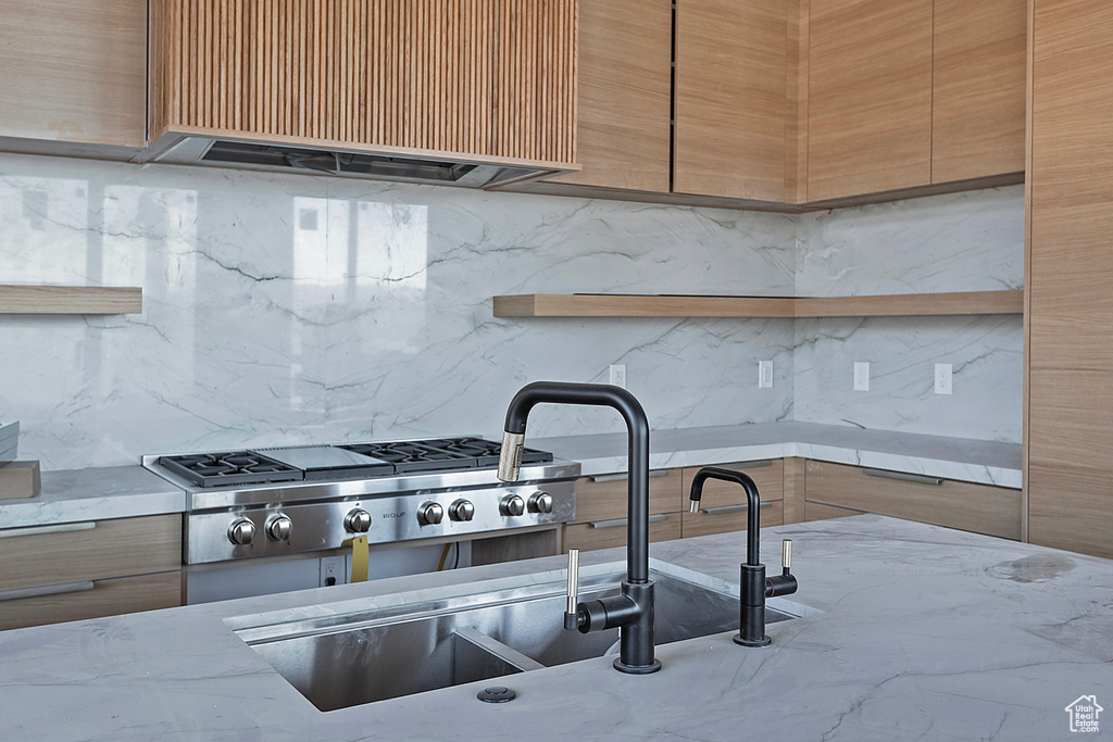 Kitchen with decorative backsplash, stainless steel gas cooktop, and exhaust hood