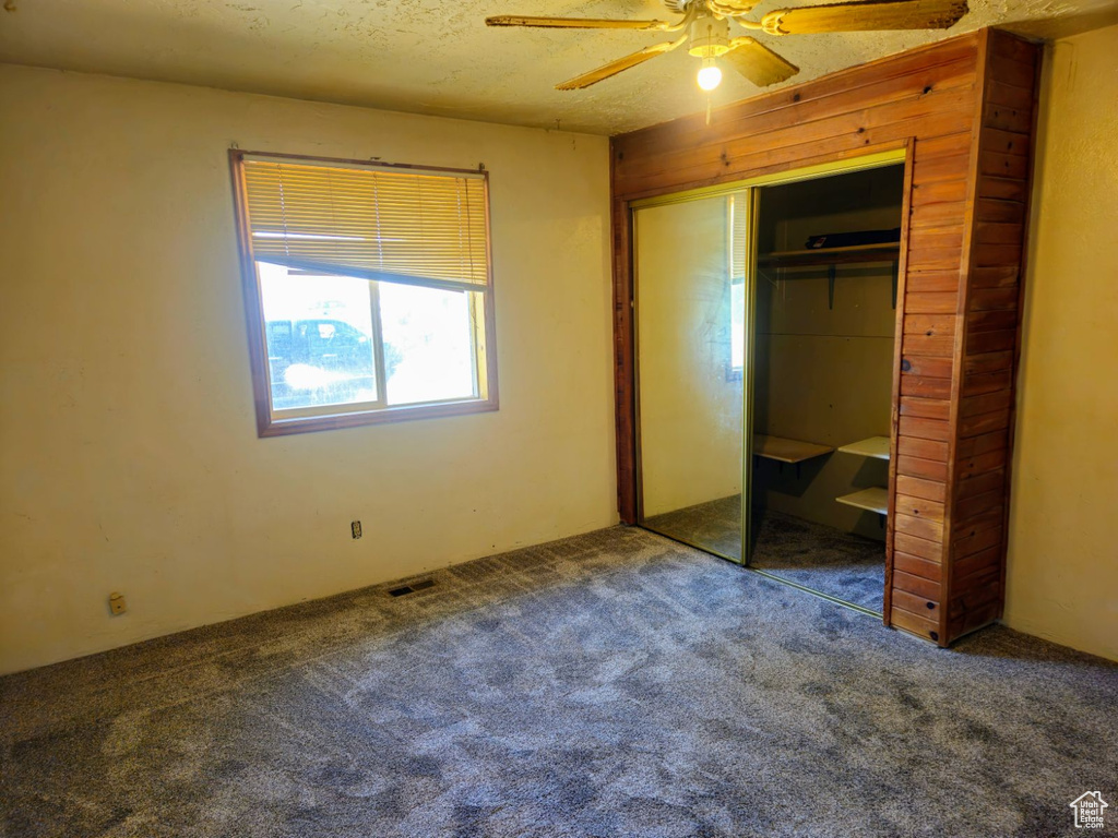 Unfurnished bedroom with carpet, a textured ceiling, ceiling fan, and a closet