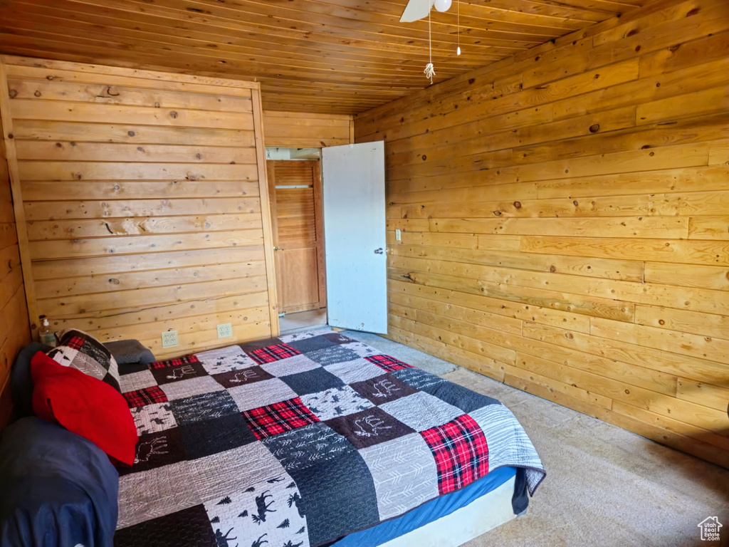 Bedroom with carpet, wood walls, wood ceiling, and ceiling fan