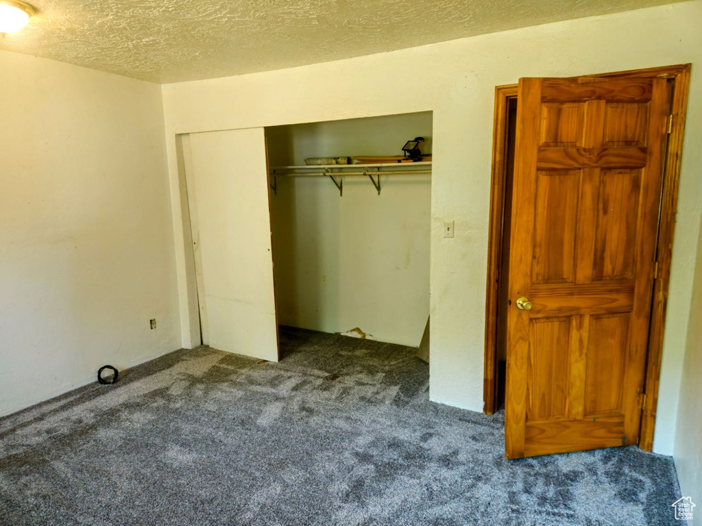 Unfurnished bedroom with a closet, a textured ceiling, and carpet floors