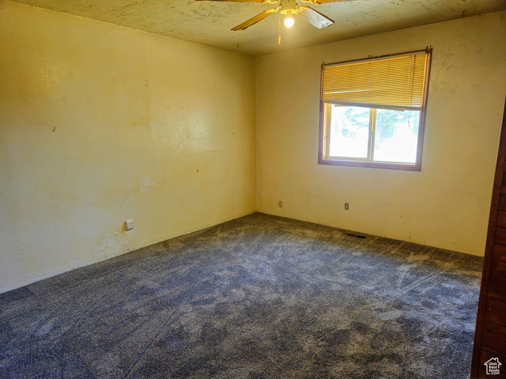 Carpeted empty room featuring a textured ceiling and ceiling fan