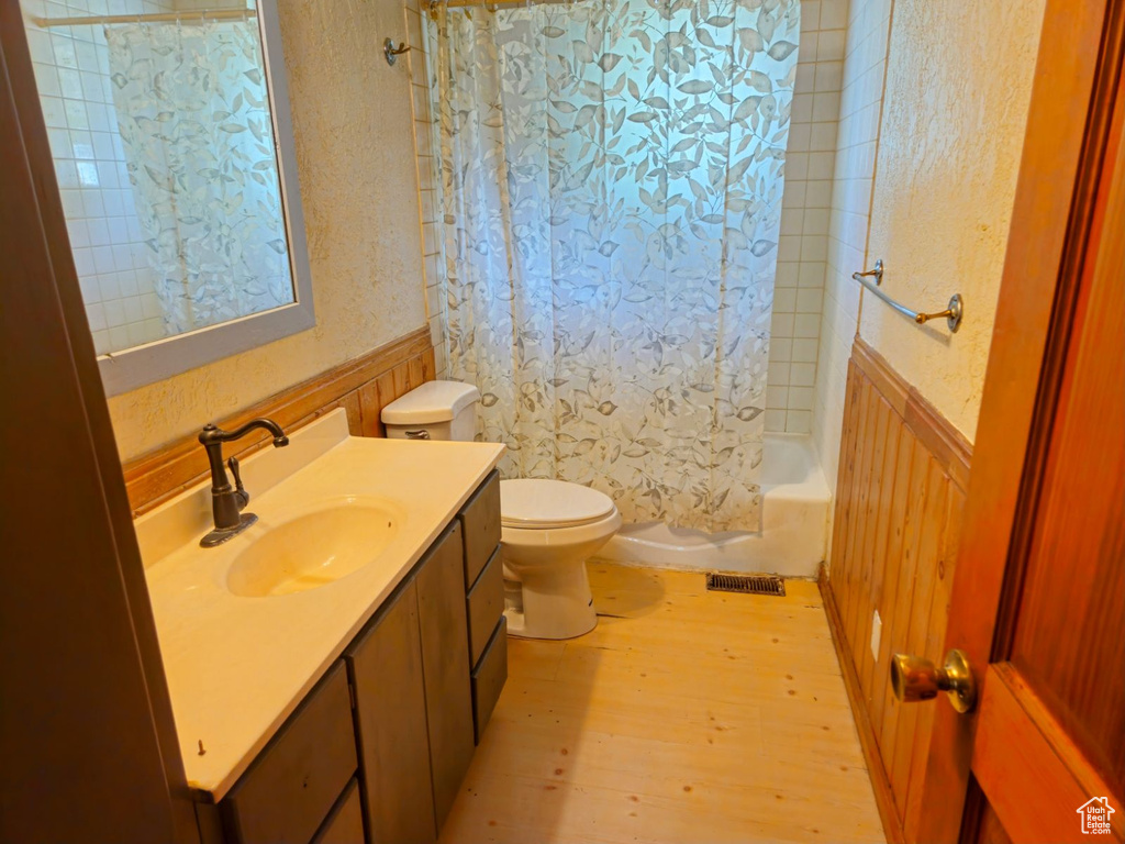 Full bathroom featuring vanity, toilet, shower / tub combo with curtain, and hardwood / wood-style floors