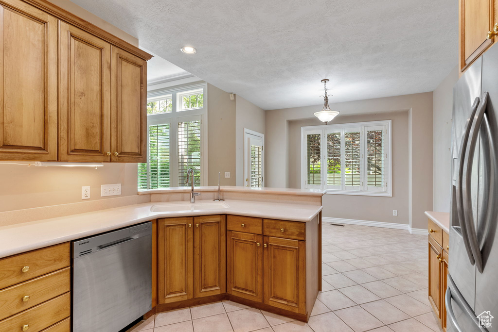 Kitchen featuring appliances with stainless steel finishes, sink, light tile patterned flooring, and pendant lighting