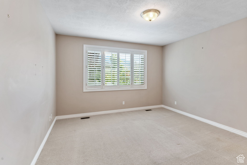 Carpeted empty room with a textured ceiling