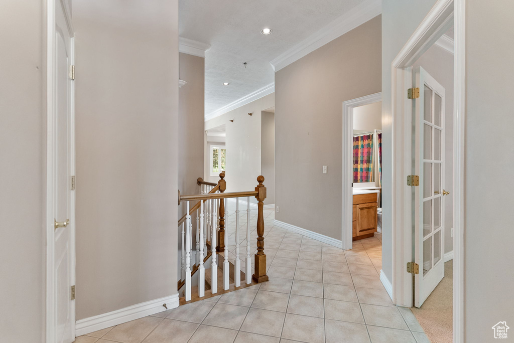 Corridor featuring ornamental molding and light tile patterned floors