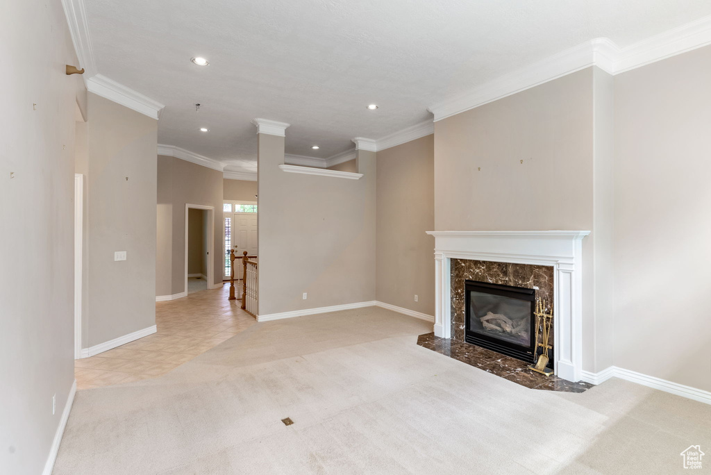 Unfurnished living room with carpet, a high end fireplace, and ornamental molding