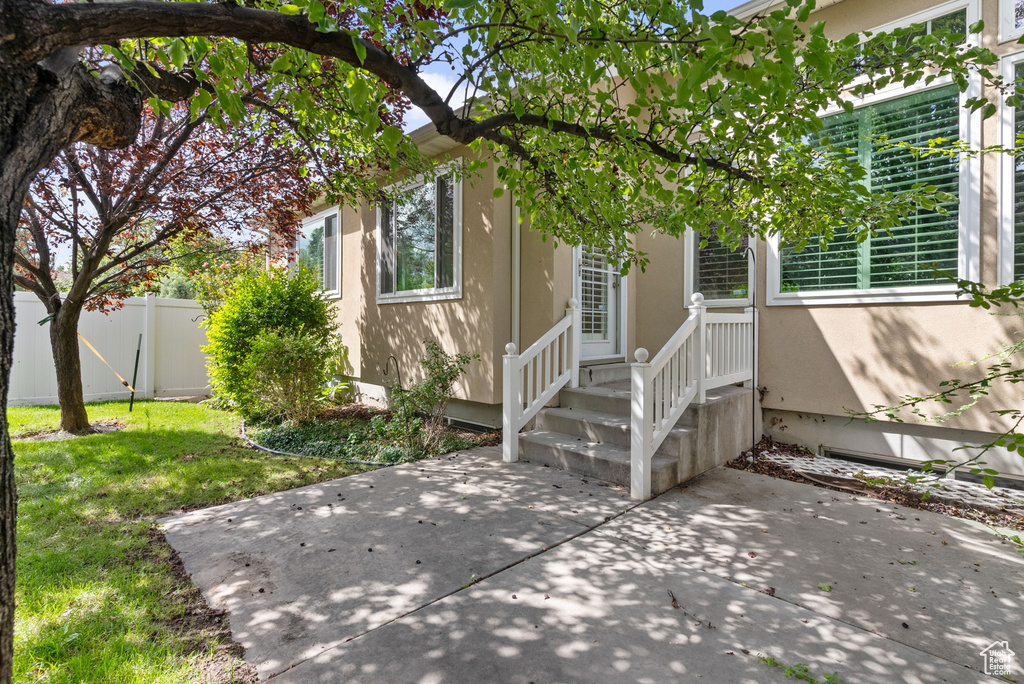 View of exterior entry with a yard and a patio