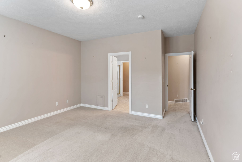 Unfurnished bedroom with a textured ceiling and light carpet