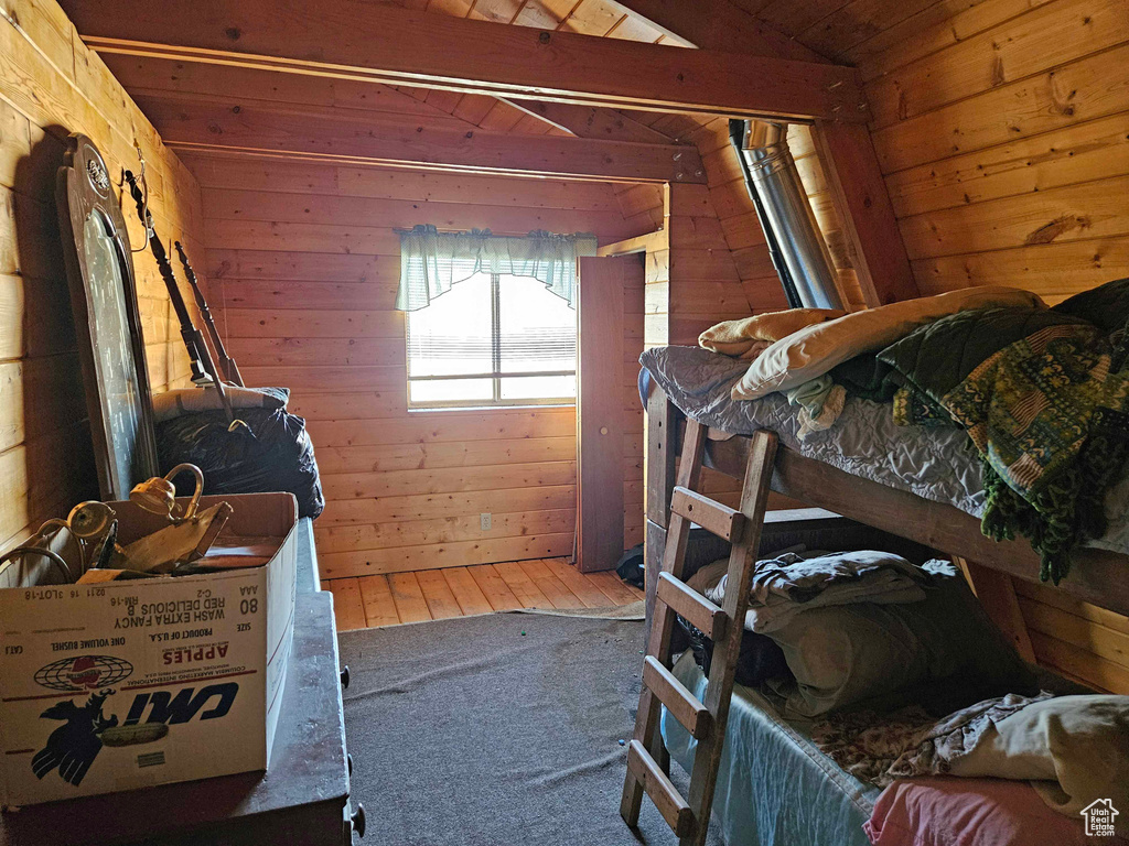Carpeted bedroom featuring wooden walls, wooden ceiling, and vaulted ceiling