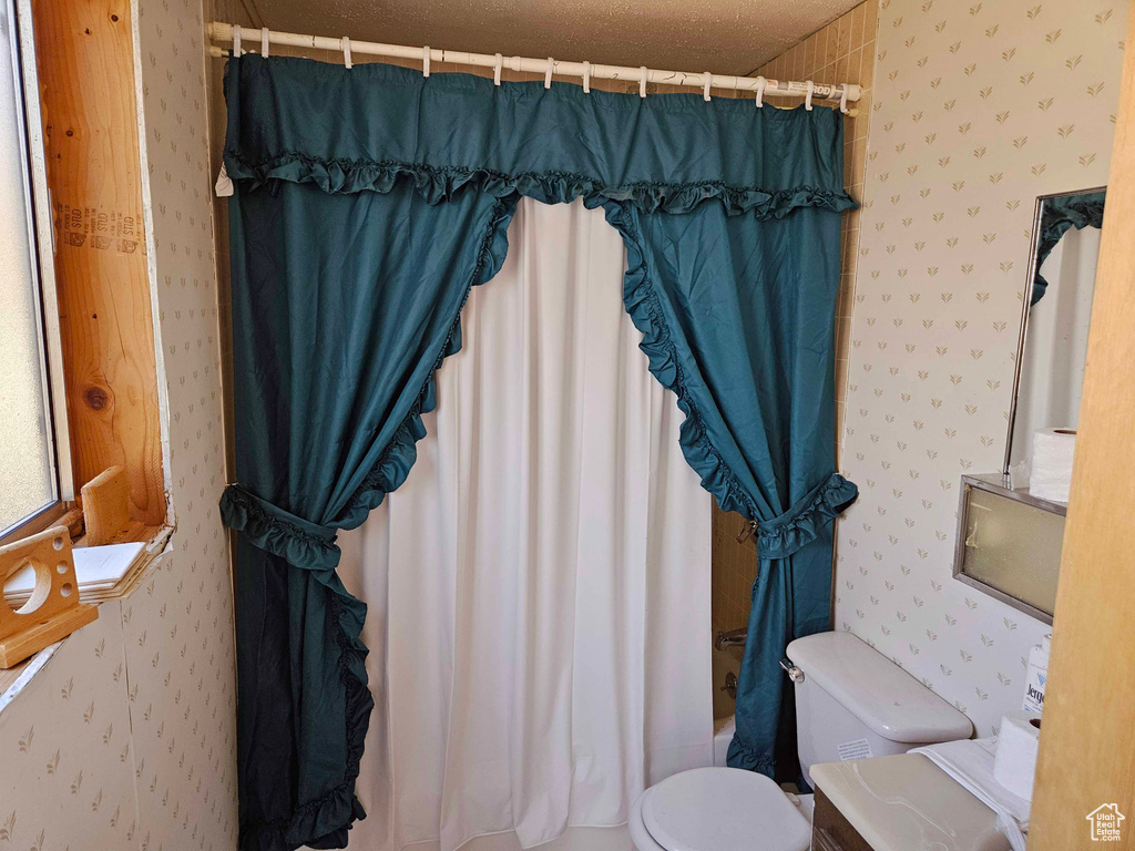 Bathroom with shower / tub combo with curtain, toilet, and wallpapered walls